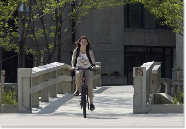 woman bicycling over bridge